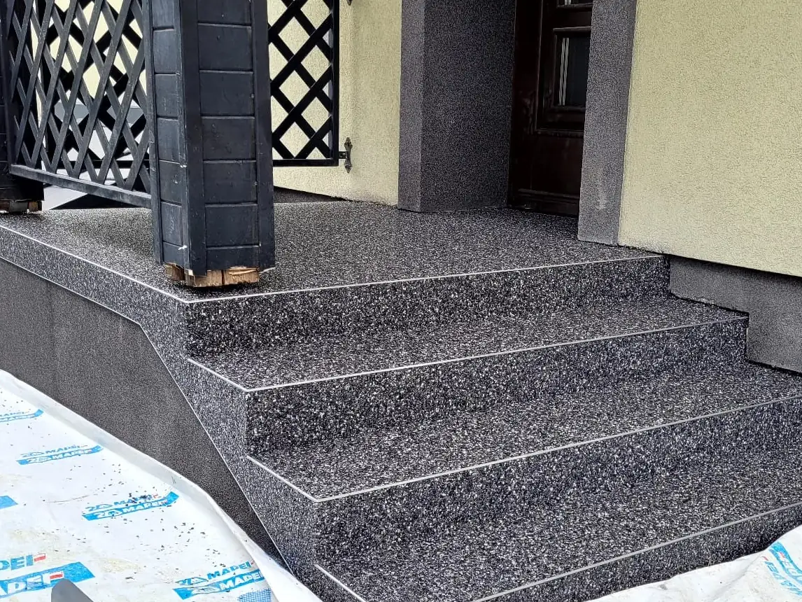 Kamienny dywan na schodach zewnętrznych z otoczaków marmurowych Grigio Carnico